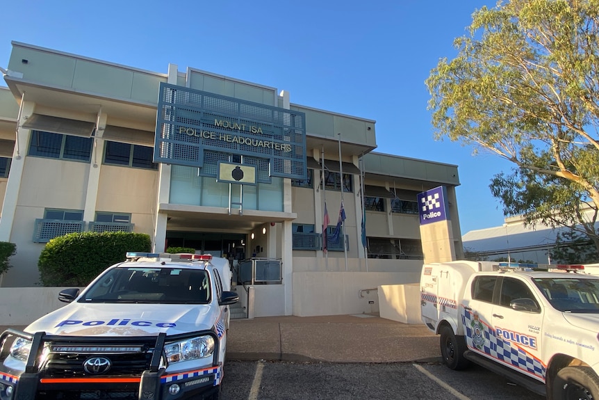 Police station with cars out front. All flags were at half mast