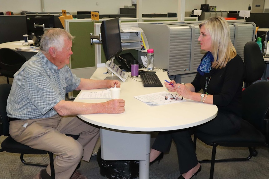 A man and a woman sitting at a round desk in an office.