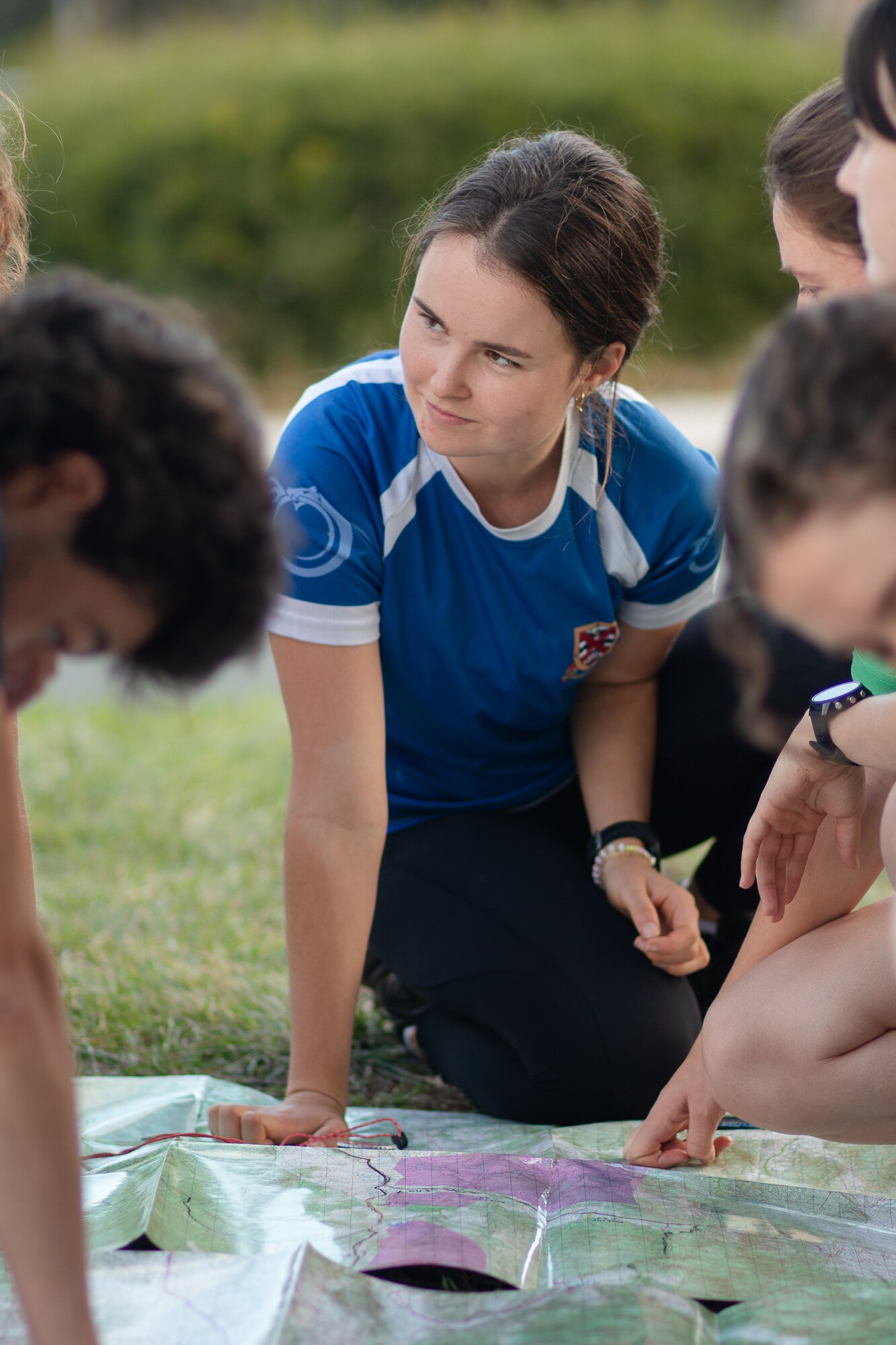 A young woman smiles while studying a map with peers.