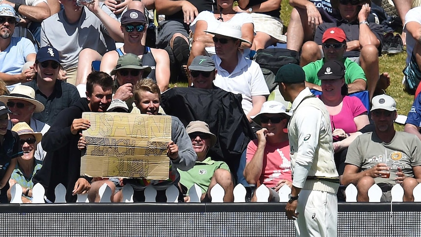 Usman Khawaja looks at a sign in the crowd pointed towards him
