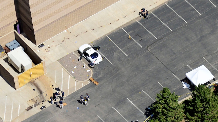 Crime scene ... Police examine James Holmes's car behind the theatre.