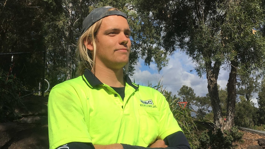 Matthew Levings poses in tradie's gear in a suburban area