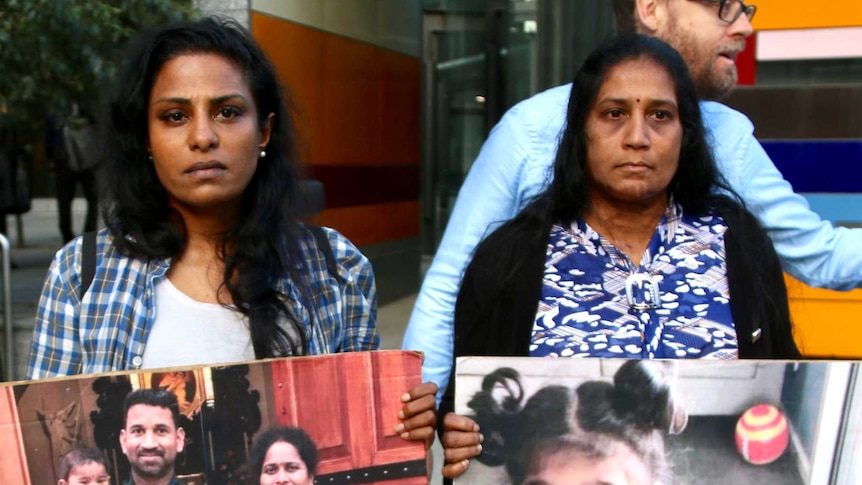 Three supporters of the Tamil asylum seeker family holding posters of the family and children outside court
