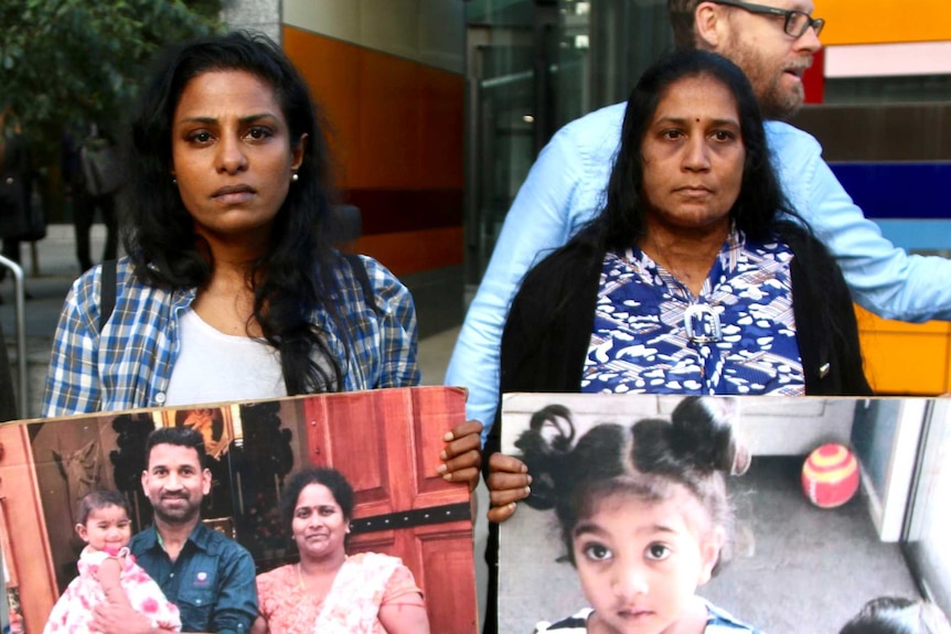 Three supporters of the Tamil asylum seeker family holding posters of the family and children outside court