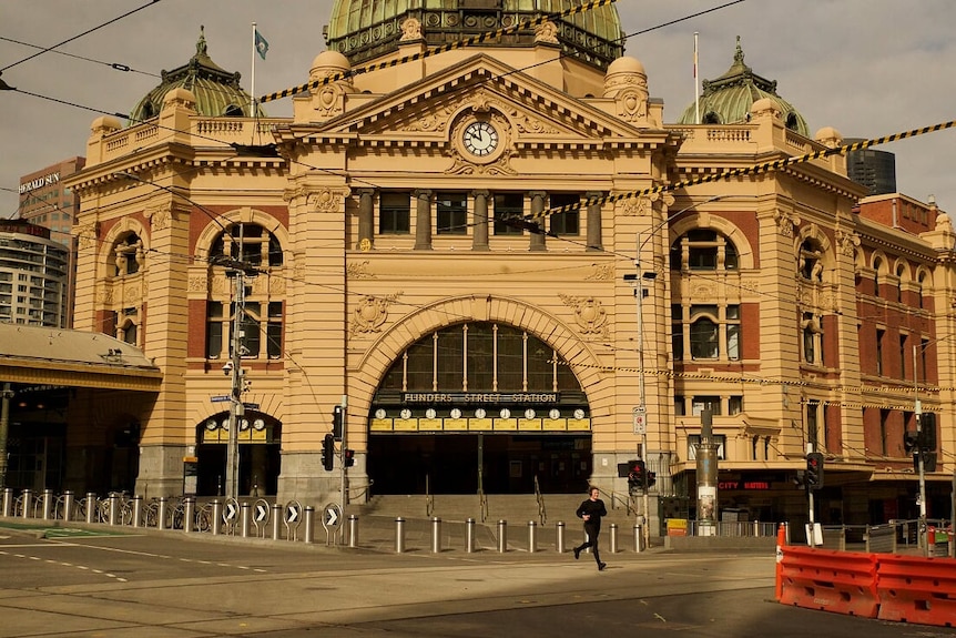 One man can be seen running across the intersection outside Flinders Street Station, otherwise empty during a Monday morning.