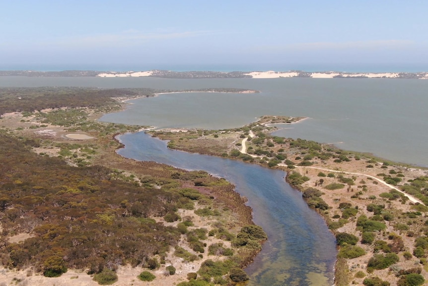 A channel and water from the air with sand dunes behind