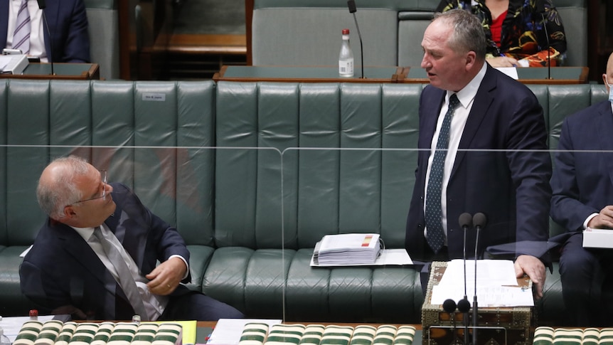 Scott Morrison watches Barnaby Joyce speaking at the lectern in parliament.