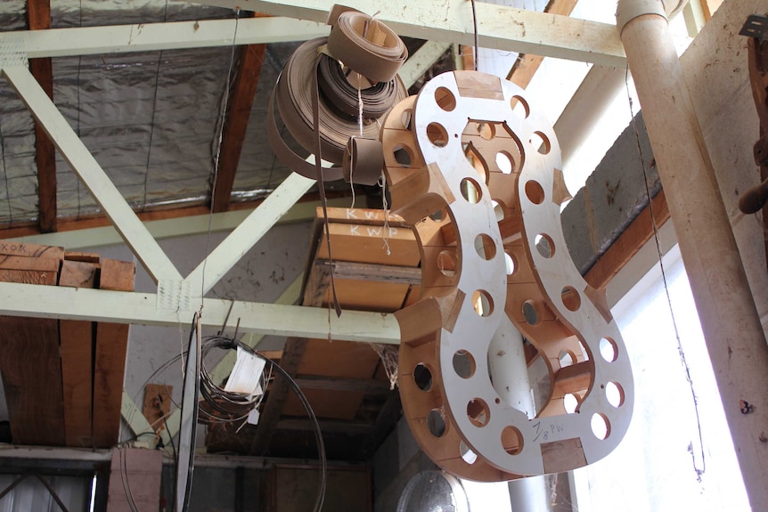 The body of a violin and other stringed instruments can be seen hanging from the ceiling in a large shed.