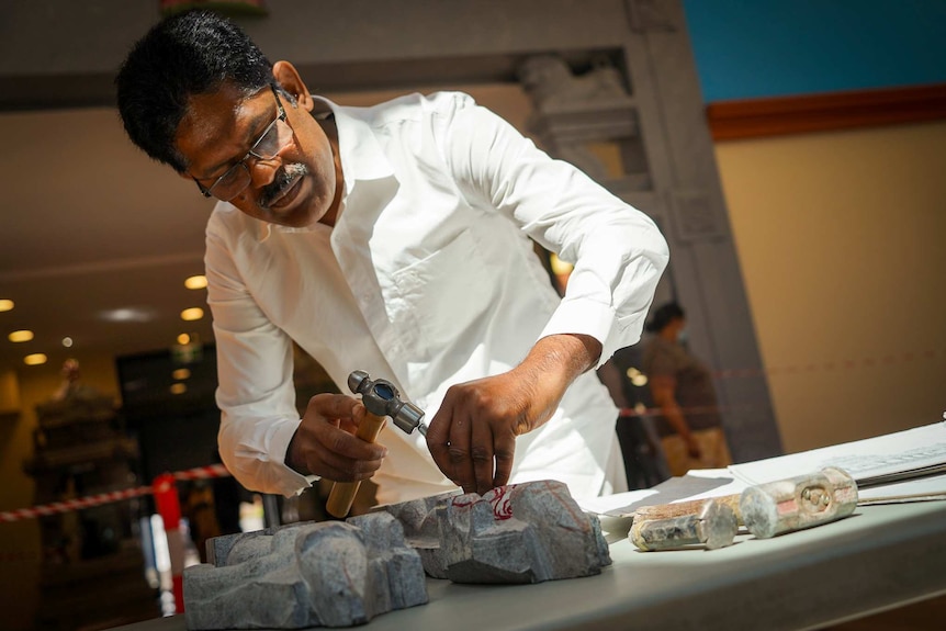 Purushothaman Jayaraman chisels a small granite statue on a table