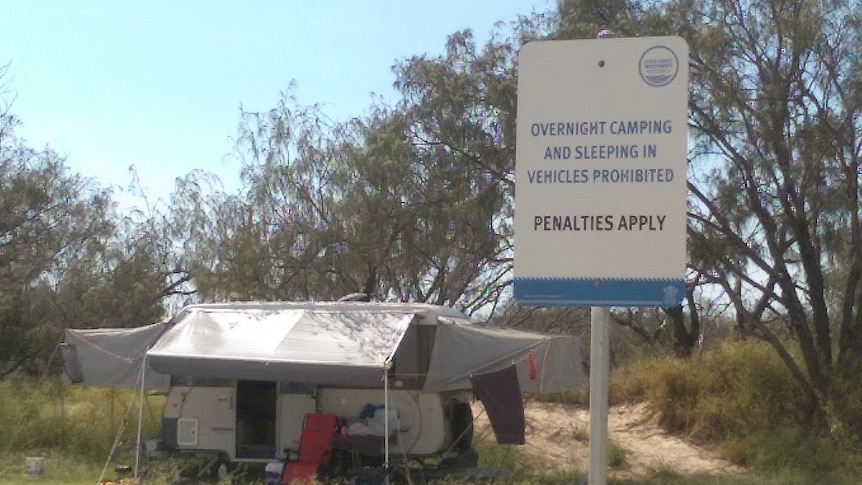 Campers set up on The Spit behind a sign prohibiting camping