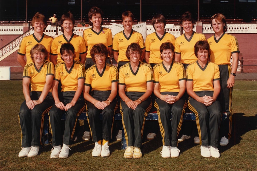 The women's Ashes team poses for a photo in green tracksuit pants and yellow t-shirts.