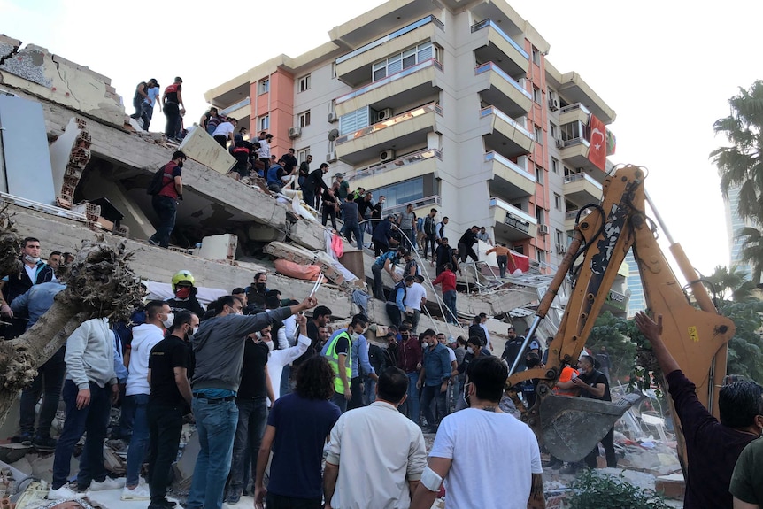 Rescue workers and local people try to save residents trapped in the debris of a collapsed building.