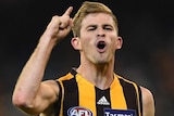 A male AFL player points a finger on his right hand and he screams out to celebrate kicking a goal.