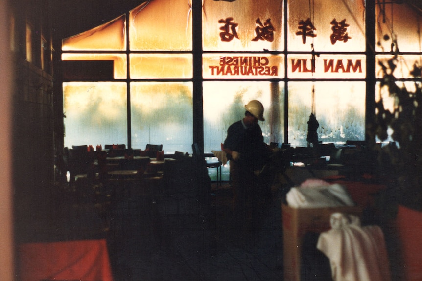 A man in a hard hat surveys the damage inside a burnt out Chinese restaurant