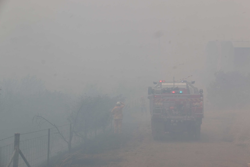 Grey smoke covers bushland and a fire truck in Beard.