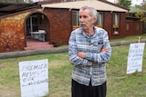 Mandogalup resident Reid Donald outside his home with protest signs attached to his fence.