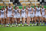 A group of Fremantle Dockers players walk off the field together.