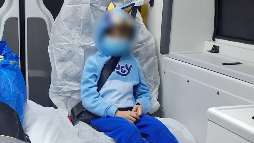 A boy sits in the back of an ambulance.