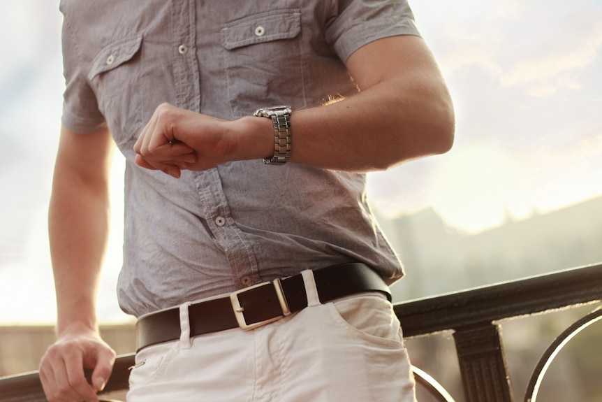 A man in casual clothes looks at his watch