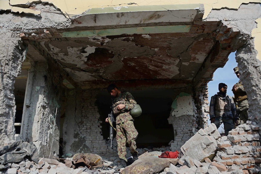 Afghan troops inspect a damaged building after a blast in Jalalabad