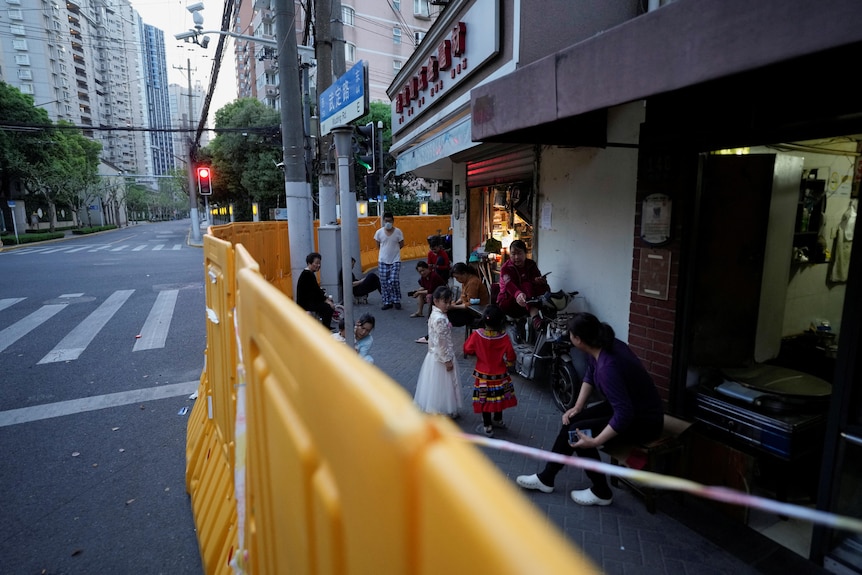 Residents stand behind barricades set around a sealed-off area, during a lockdown to curb the spread of the coronavirus disease