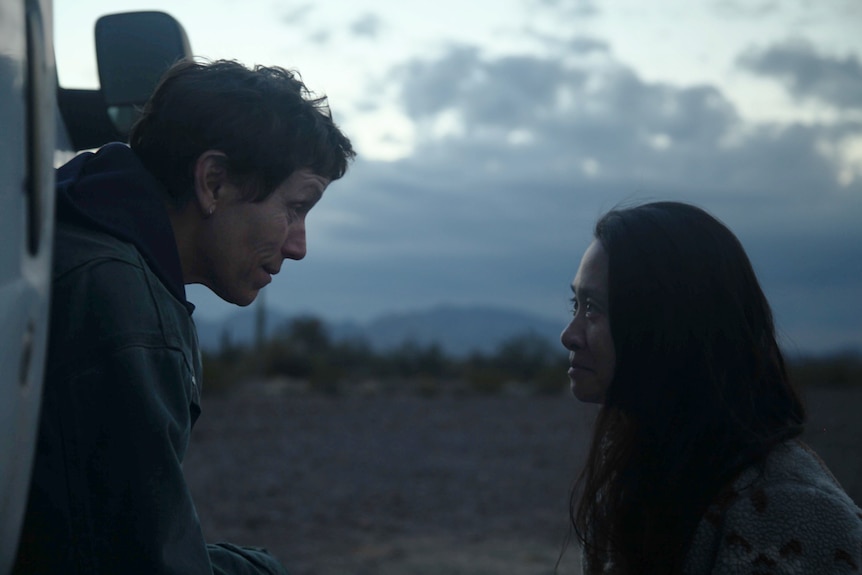 Twilight outdoors shot, side-on, with Frances sitting in van looking into face of Chloe, crouching on ground.