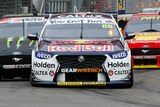 Jamie Whincup's Red Bull-branded Holden drives ahead of two Ford Mustang cars, one black and one red