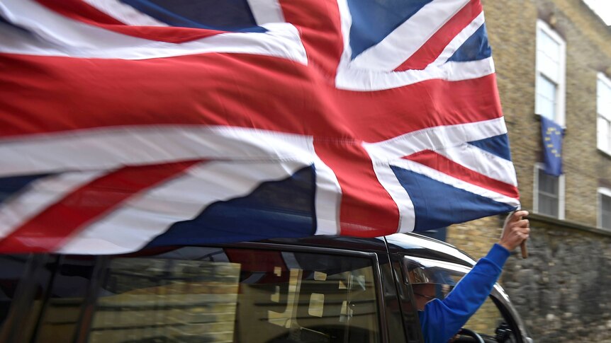 A taxi driver holds a Union flag, as he celebrates following the result of the EU referendum