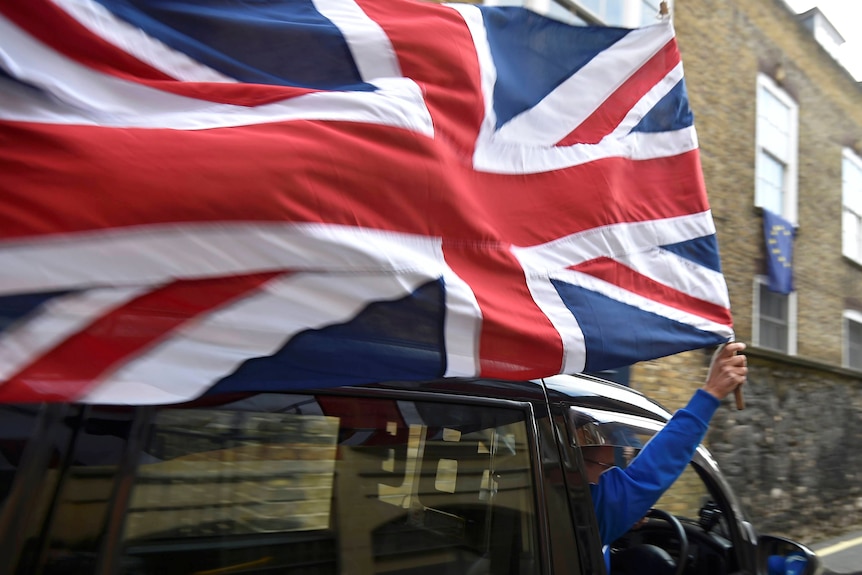 A taxi driver holds a Union flag, as he celebrates following the result of the EU referendum