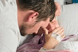 A man and woman share grief while cradling their stillborn daughter.