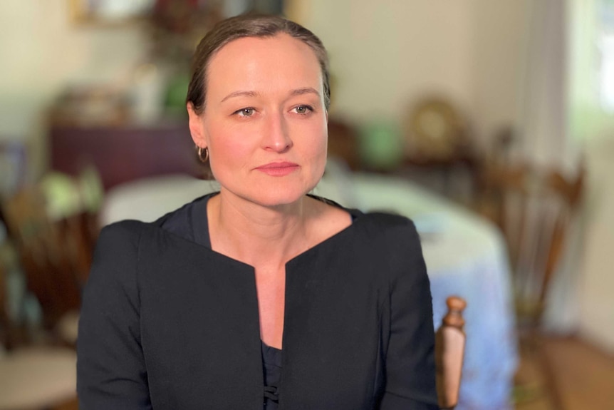 Woman in dining room looks to the right of the camera