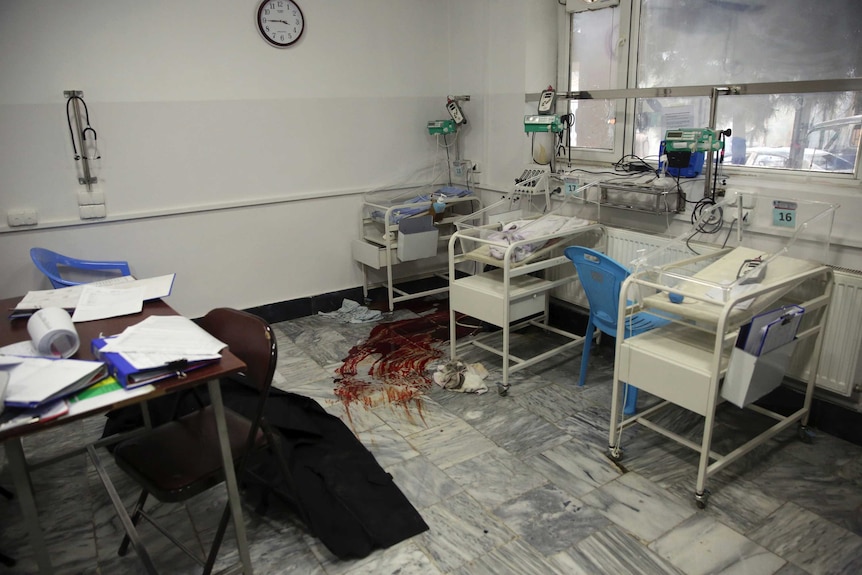Blood stains the floor of a hospital ward with baby cribs.