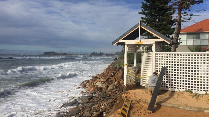 A Narrabeen resident secures the back fence of his home which backs onto the water.