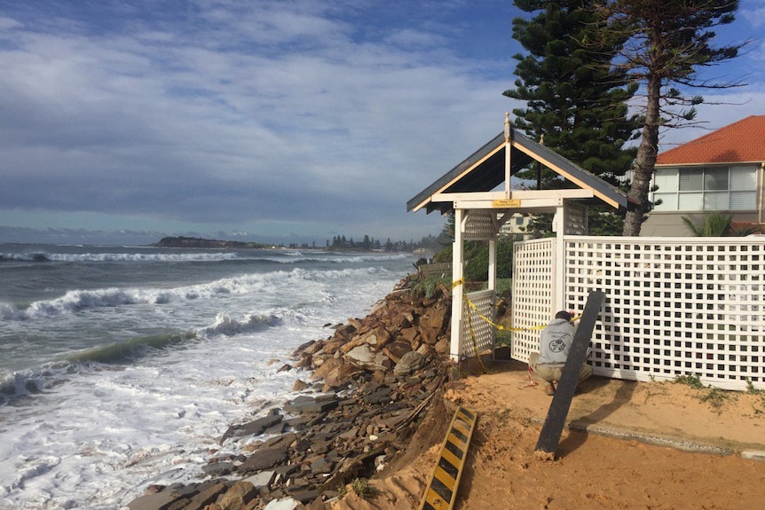 A Narrabeen resident secures the back fence of his home which backs onto the water.
