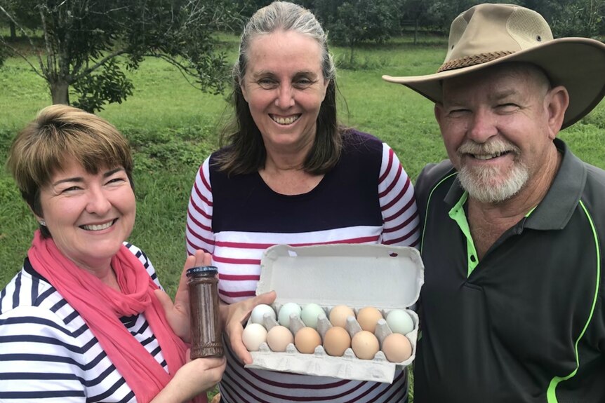 Helen Andrew, Sharon and Glenn Otto swapping a jar of mango chutney for eggs.