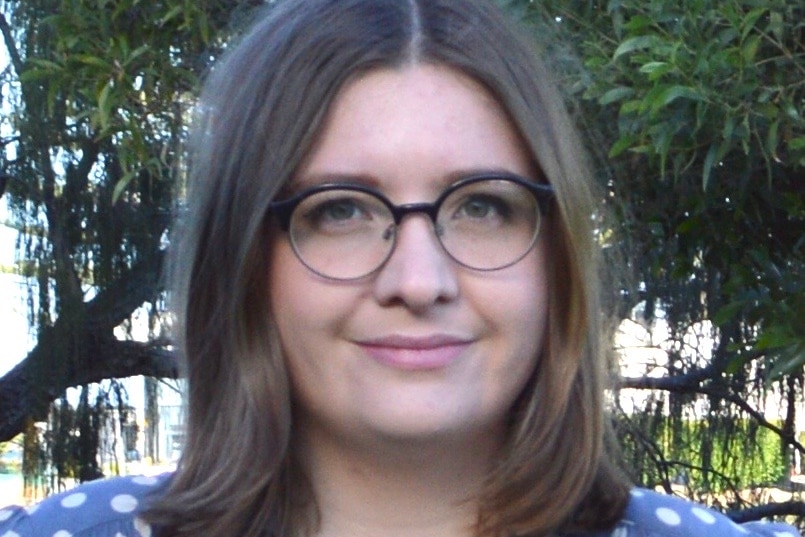 A woman with dark brown hair wearing glasses and a polka dot shirt.