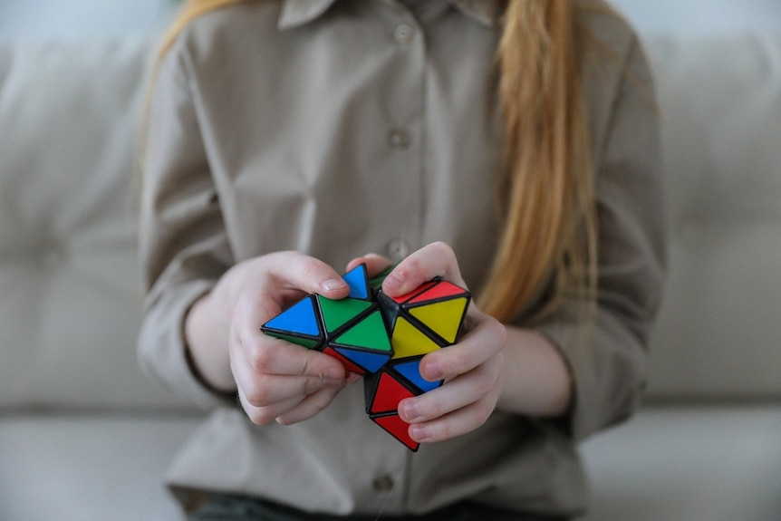A photo of a woman trying to solve a rubik's cube