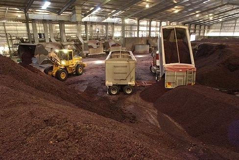 Trucks load and unload wine waste made up of stems, seeds and skins