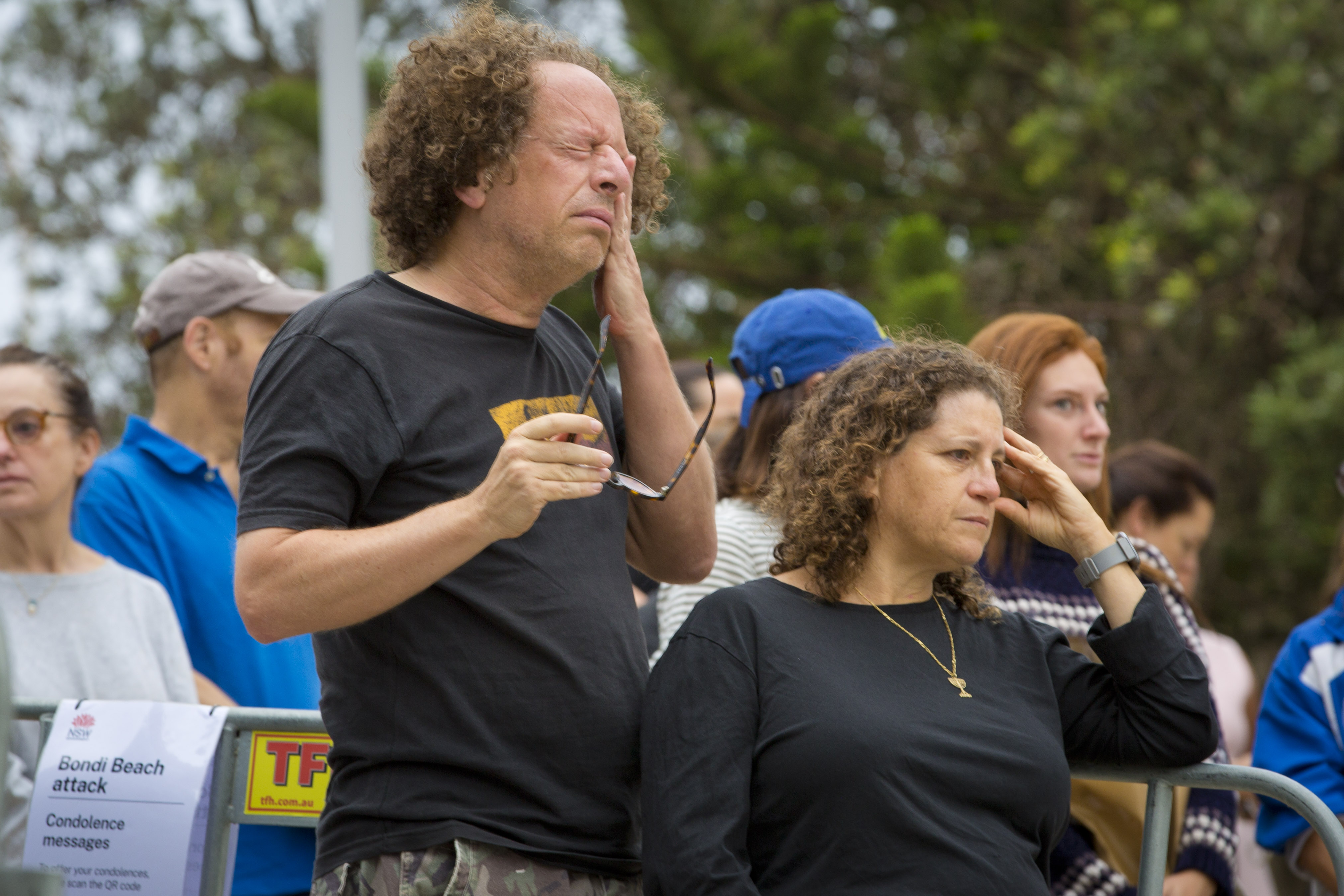 Um homem enxuga uma lágrima e segura os óculos na mão direita