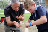 Alex Murchison demonstrates didgeridoo making with a student filing a didgeridoo in a lathe.