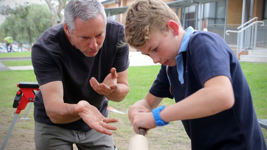 Alex Murchison demonstrates didgeridoo making with a student filing a didgeridoo in a lathe.