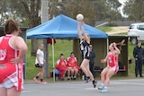 woman in centre going for netball on court.