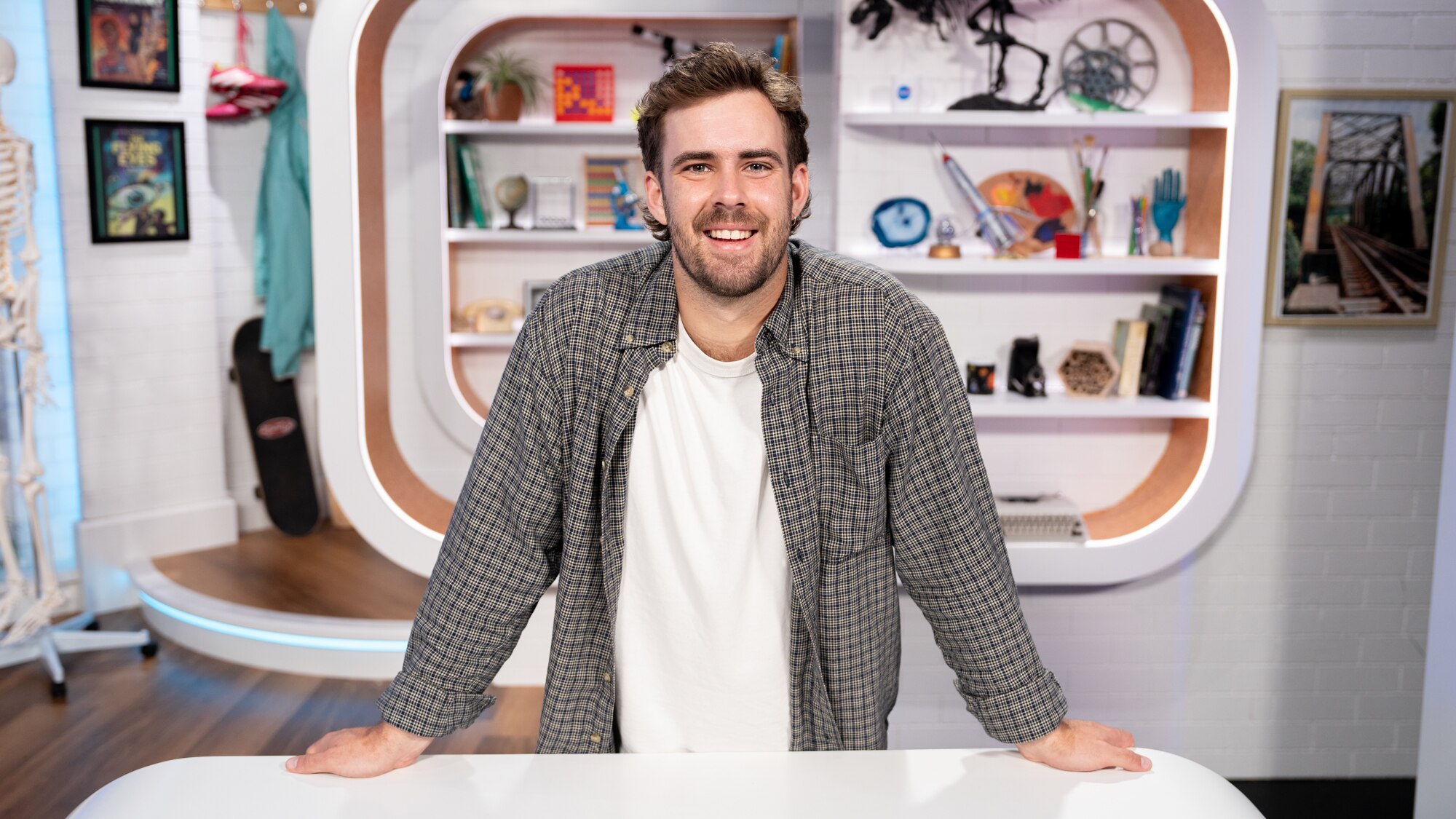 Cale leans on the BTN studio desk smiling to camera.