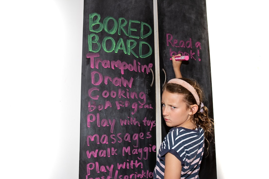 Girl writing a list of activities that don't involve screens in a story about reducing screen time to engage with kids.