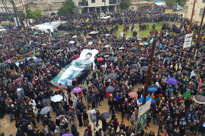 Protestors wave a giant poster of jailed PKK leader Abdullah Ocalan during a demonstration against Turkish threats in Afrin