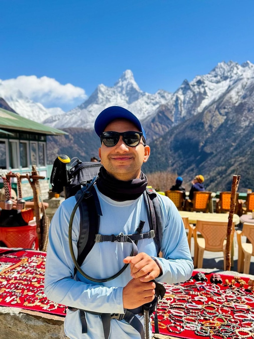 Ram Khanal smiles while standing in front of a snow-capped mountain.
