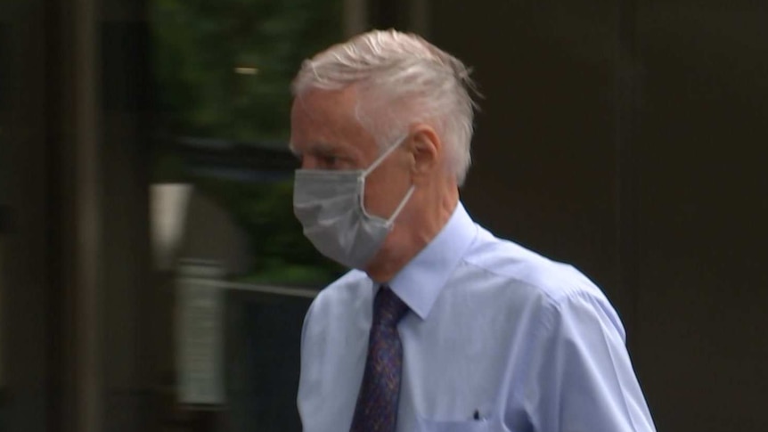 Neil Lennie, wearing a shirt, tie and face mask, walks into court.