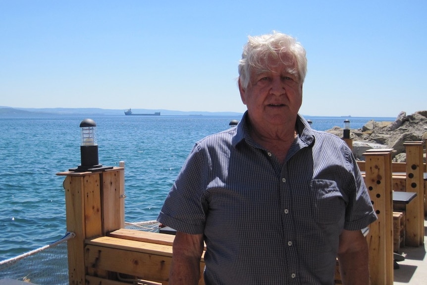 Older man standing with ocean in background
