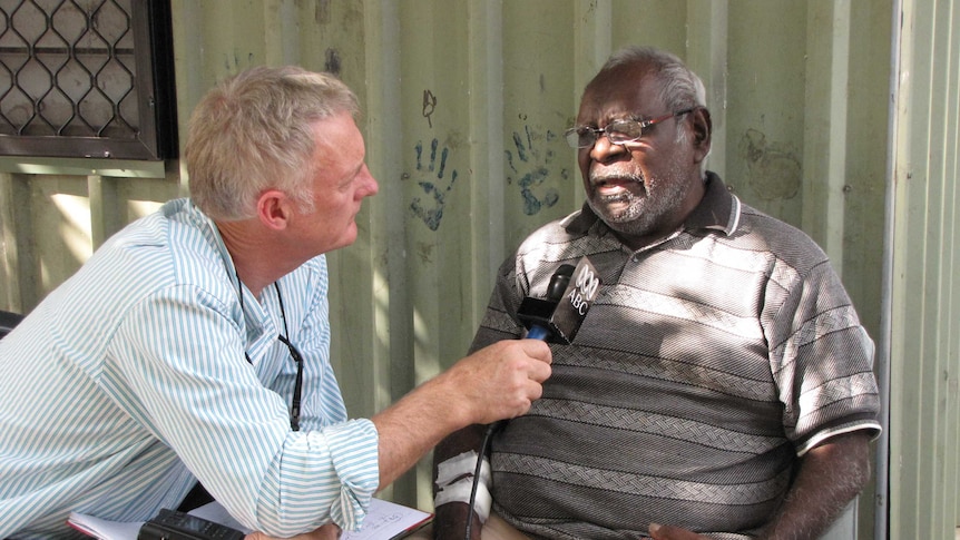 Tony Eastley holds a microphone while interviewing a Darwin man in 2010.