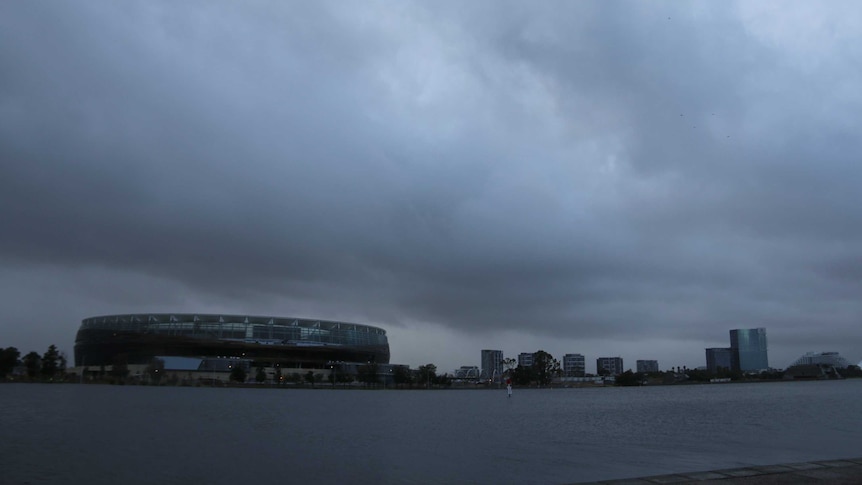 Dark rain clouds hang over Perth Stadium and high-rise buildings with the Swan River stretching out in front.